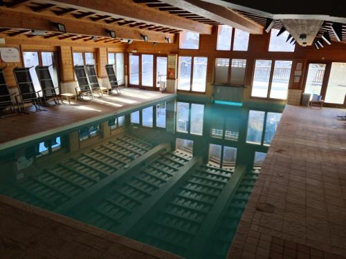 une piscine avec des chaises dans un immeuble dans l'établissement Arc 1950 Appartement de standing Refuge du Montagnard, vue incroyable sur le Montblanc, skis aux pieds Accès spa et piscine, à Arc 1950