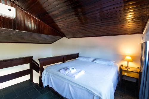 ein Schlafzimmer mit einem weißen Bett und einer Holzdecke in der Unterkunft HOTELARE Hotel Villa Di Capri in Ubatuba