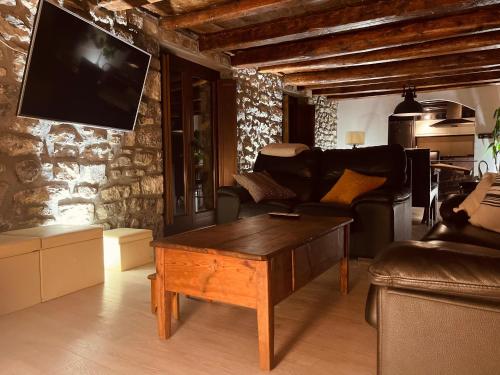 a living room with a couch and a tv on a stone wall at Casa Valle Duplex de montaña in Panticosa