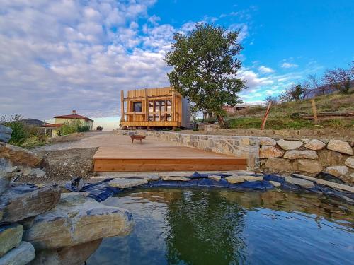 a wooden house with a pond in front of it at Panorama glamping Vipavska dolina in Dobravlje