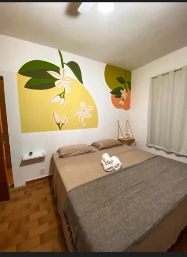 a bedroom with a bed with flowers on the wall at Nosso Recanto Pérola in Capitólio
