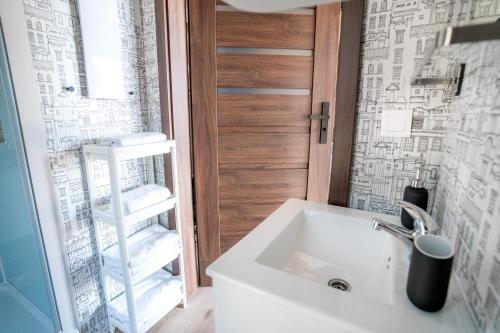 a bathroom with a sink and a glass door at Ruciane Park - Mazury resort & spa in Ruciane-Nida