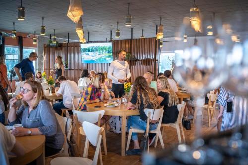 Ruciane Park - Mazury resort & spa في روسيان-نيدا: مجموعة من الناس يجلسون على الطاولات في المطعم