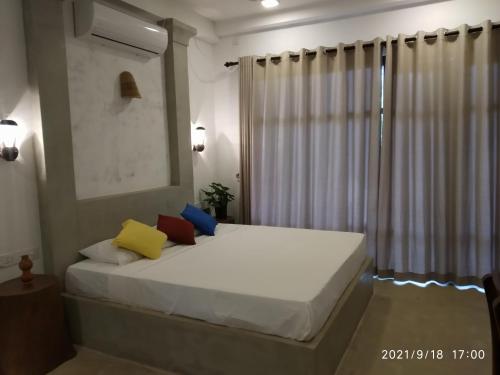 a bedroom with a white bed and a window at Guruwaththa Eco Lodge in Hikkaduwa
