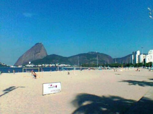 a beach with a sign in the sand and mountains at Aragão Botafogo Studio in Rio de Janeiro