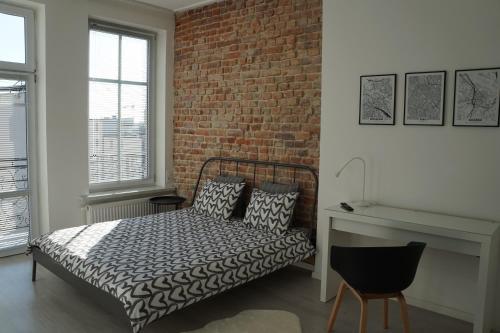 een slaapkamer met een bed en een bakstenen muur bij Apartament Gliwice Centrum Witkiewicza II in Gliwice