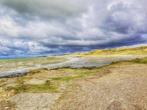 a beach with a cloudy sky and the ocean at Gite Beaulieu in Wimereux