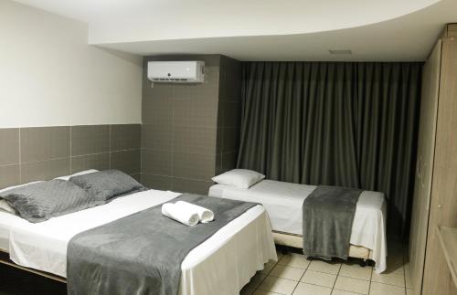 twee bedden in een hotelkamer met handdoeken erop bij Atlântico Flat Natal in Natal