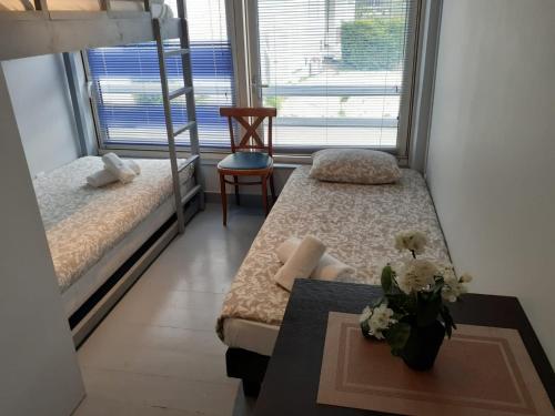 a room with two beds and a vase of flowers on a table at Apparthotel AREA, Studios avec salle de bain et kitchenette Privées, OU, chambres avec salles bain et cuisines communes in Persan