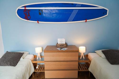 a room with two beds and a surfboard on the wall at Red Star Surf & Yoga Camp Lanzarote in Famara