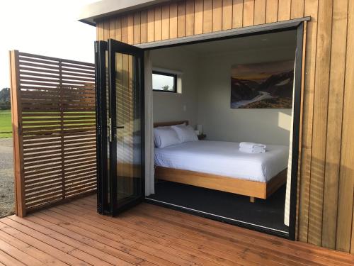 sypialnia z łóżkiem i dużymi szklanymi drzwiami w obiekcie Alpine Escape w mieście Franz Josef