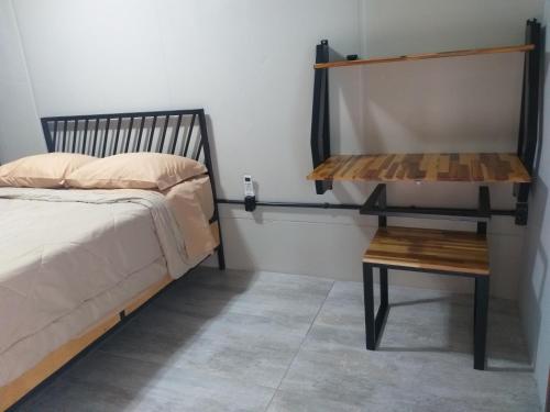 1 dormitorio con cama y mesa de madera en Pousada Mirra, en Penha