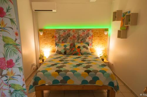 a bedroom with a bed with a green light at Résid’calonne in Le François