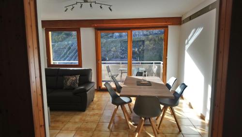 a dining room with a table and chairs and a couch at Apart'Bellevue in Morez