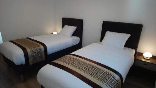 two beds in a hotel room with white sheets at Apart'Bellevue in Morez