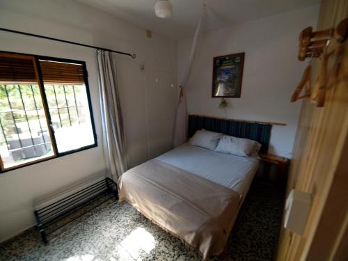 La Tierra Verde COTTAGE في Alcuéscar: غرفة نوم صغيرة بها سرير ونافذة