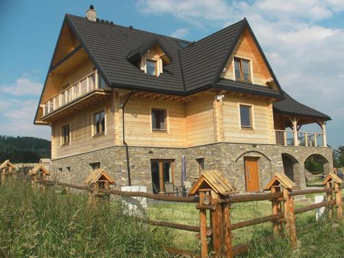 a house with a black roof on top of a field at Willa Grywałd in Grywałd