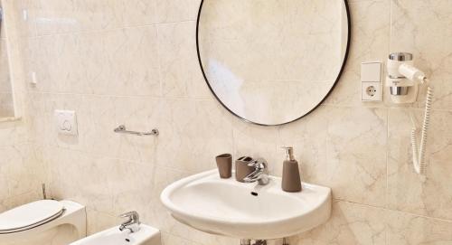 uma casa de banho com um lavatório, um espelho e um WC. em Rosa Rooms Meran em Merano