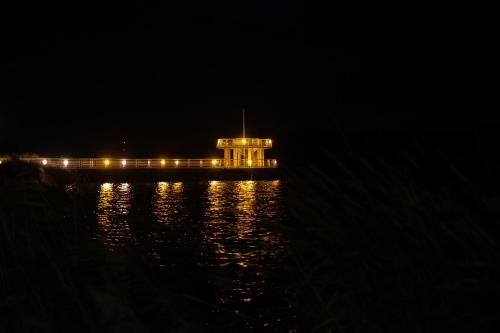 a building with lights on the water at night at NIENOVO - Apartament Kórnik niedaleko jeziora i widok na Arboretum in Kórnik