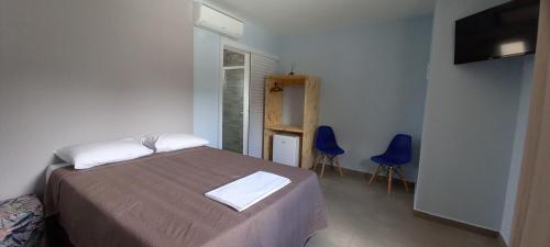 a bedroom with a bed and two blue chairs at Fric Pousada in Ubatuba