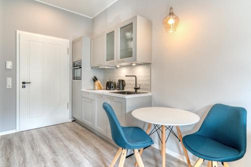 a kitchen with two blue chairs and a table at One Moment Boardinghouse - Apartment Harmony in Porta Westfalica