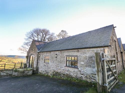an old stone house with a gate in front of it at The Barn at Hill House in Buxton