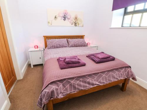 a bedroom with a bed with purple blankets and pillows at The Barn at Hill House in Buxton
