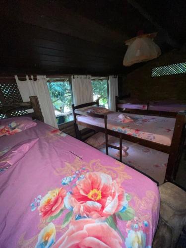 a bedroom with a pink bed with flowers on it at Hostel do Ceu in Pipa