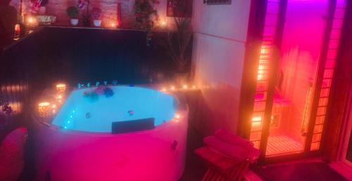 - une baignoire dans une chambre avec des lumières roses dans l'établissement La Romance jacuzzi sauna jardin au calme, à Niort