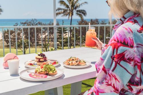 uma mulher de pé numa mesa com pratos de comida em The Pink Hotel Coolangatta em Gold Coast