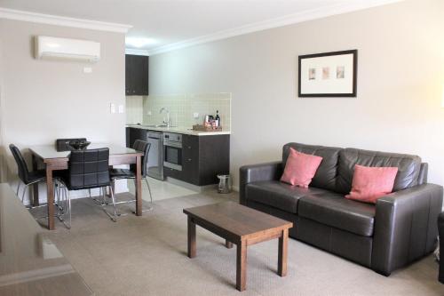 - un salon avec un canapé et une table dans l'établissement Carlyle Suites & Apartments, à Wagga Wagga