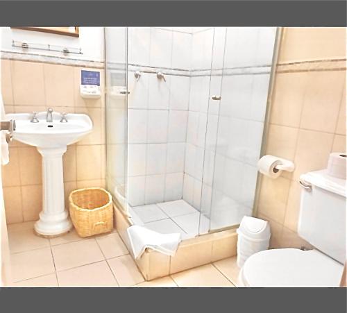 a bathroom with a shower and a sink and a toilet at Hotel Cantuña in Quito