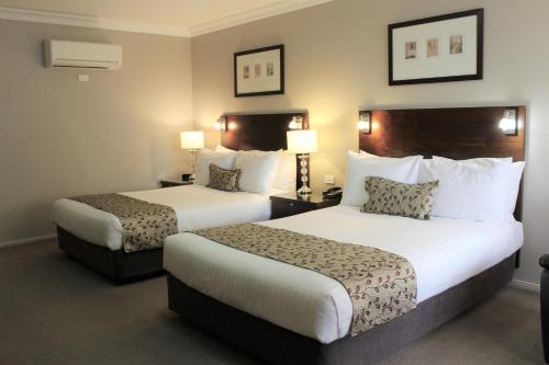 Habitación de hotel con 2 camas y 2 lámparas en Carlyle Suites & Apartments en Wagga Wagga