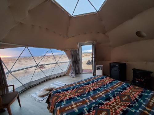 a bed in a room with a view of the desert at The Kosmic Tortoise in Twentynine Palms