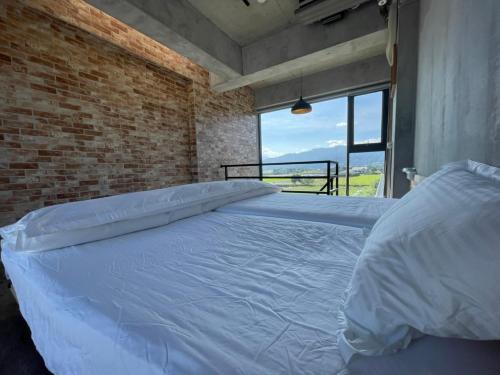 a large white bed in a room with a brick wall at Bafentian Farmhouse in Guilin