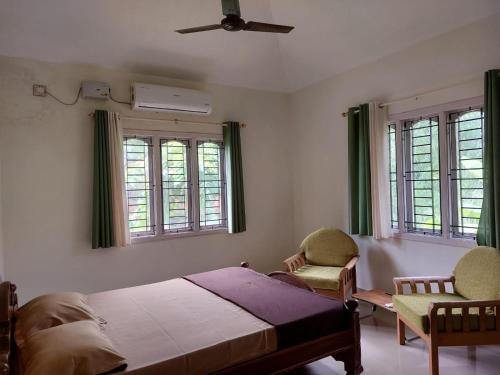 a bedroom with a bed and two chairs at Tharavad Holiday Home in Mangalore