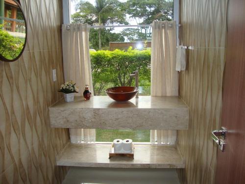 a bathroom with a bowl on a counter with a window at Minha Casinha Azul na Represa in Paranapanema