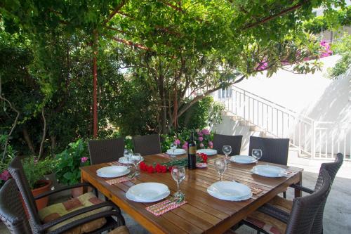 a wooden table with plates and wine glasses on it at NEW comfortable Apartment Vesna in Hvar