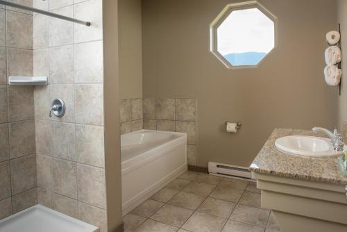 een badkamer met een douche, een bad en een wastafel bij Hilltop Inn - Salmon Arm in Salmon Arm