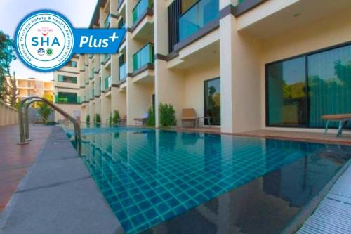 a swimming pool in front of a building at Airport Beach Hotel Phuket in Nai Yang Beach