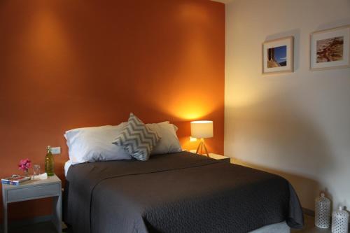 a bedroom with a bed and a orange wall at La Betulia Bed and Breakfast in Oaxaca City