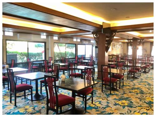 una sala da pranzo con tavoli, sedie e finestre di Dad D Resort by Lopburi Inn Resort a Lopburi