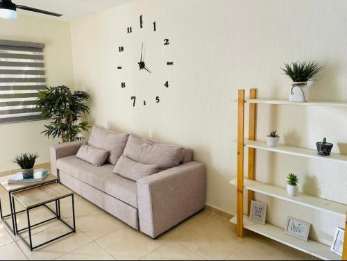 sala de estar con sofá y reloj en la pared en Hermosa casa para familias grandes/12 personas, en Playa del Carmen