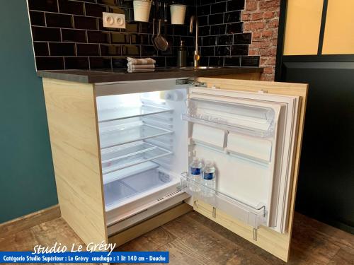 an empty refrigerator with its door open in a kitchen at Nos studios au centre ville à Dole in Dole
