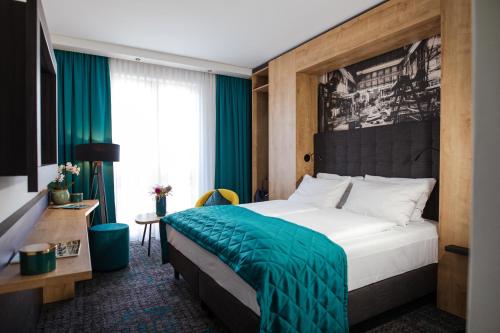 a hotel room with a bed with a green blanket at Das Steinmüller Hotel in Gummersbach