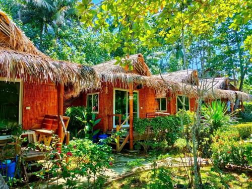 a house with a thatched roof and a patio at Mook Montra Resort Sea Front in Koh Mook