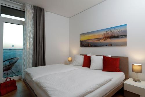 a white bedroom with a large bed and a window at Triiiple Suites Level 21 mit Balkon und Tiefgarage in Vienna