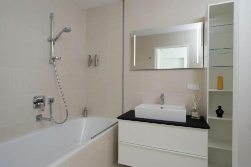 ein Badezimmer mit einer Badewanne, einem Waschbecken und einem Spiegel in der Unterkunft Triiiple Suites Level 21 mit Balkon und Tiefgarage in Wien