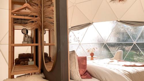 um quarto com uma cama e uma grande janela em Romantische glamping dome Koksijde - Duiniek em Koksijde