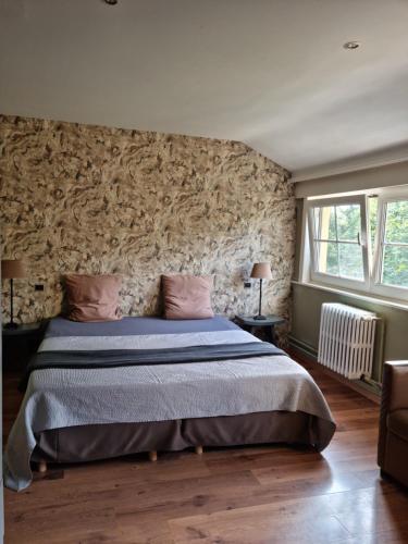 een slaapkamer met een groot bed en een stenen muur bij Manoir du bois des rêves in Lacroix